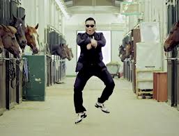 A still image from PSI's music video for "Gangnam Style" showing him dancing in a horse stable.