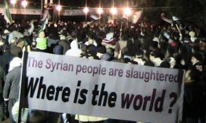 Syrian protesters with a sign reading "The Syrian people are slaughtered; where is the world?"